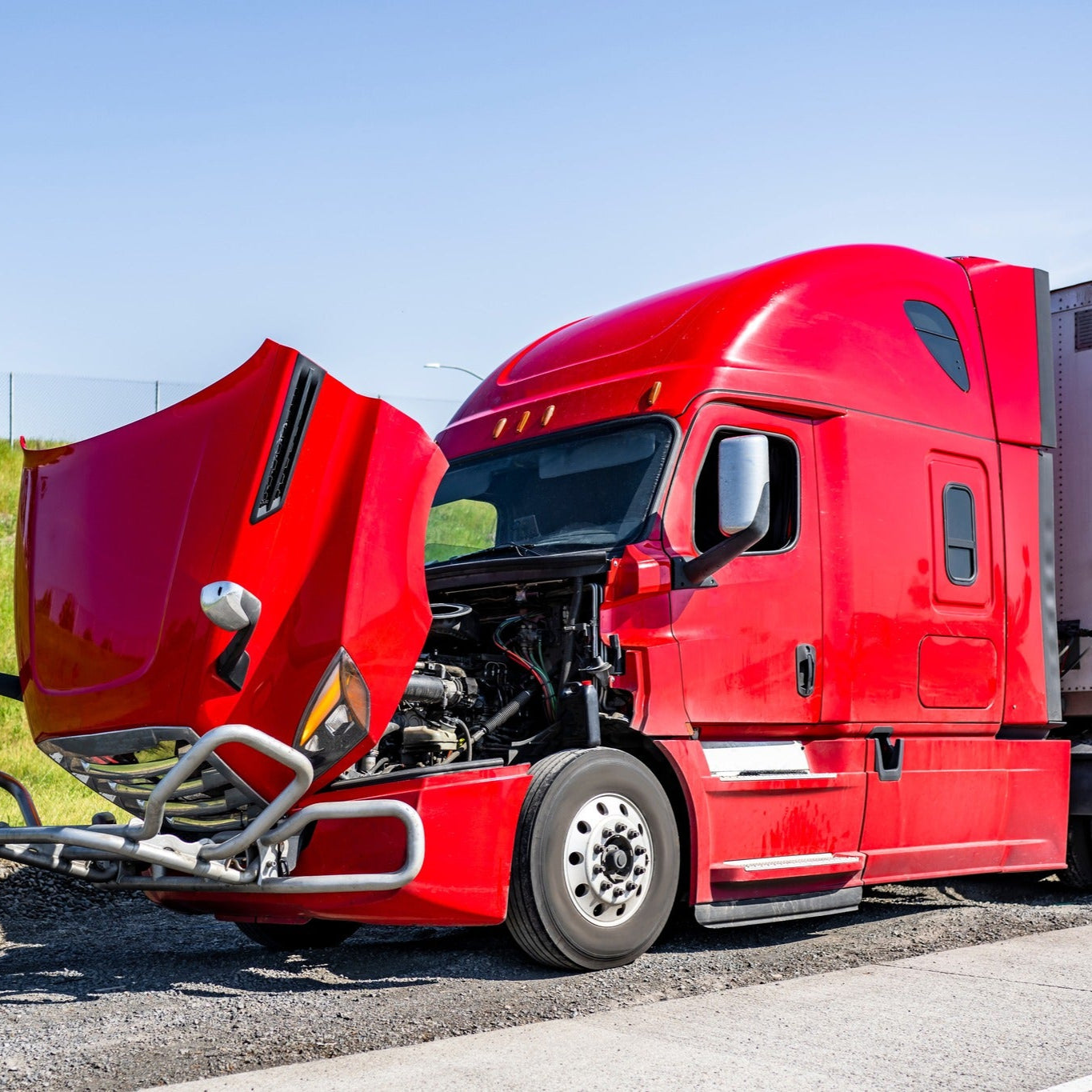 Red semi-truck with a trailer on a side of road